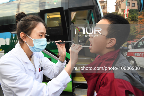 A health care worker is checking a student before administering a flu shot in Guiyang, Guizhou Province, China, on November 24, 2023. 