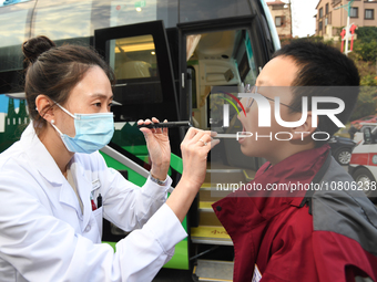 A health care worker is checking a student before administering a flu shot in Guiyang, Guizhou Province, China, on November 24, 2023. (