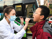 A health care worker is checking a student before administering a flu shot in Guiyang, Guizhou Province, China, on November 24, 2023. (