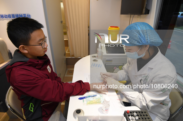 A medical worker is inoculating students against influenza on a mobile vaccination vehicle in Guiyang, Guizhou province, China, on November...