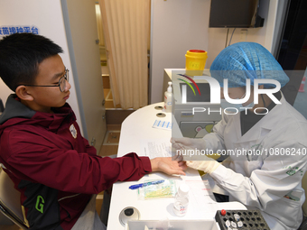 A medical worker is inoculating students against influenza on a mobile vaccination vehicle in Guiyang, Guizhou province, China, on November...