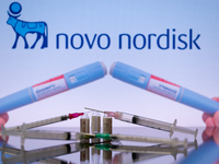 The Novo Nordisk pharmaceutical logo is being displayed on a screen alongside pills and a medical vial with a syringe in this photo illustra...