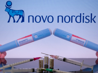 The Novo Nordisk pharmaceutical logo is being displayed on a screen alongside pills and a medical vial with a syringe in this photo illustra...