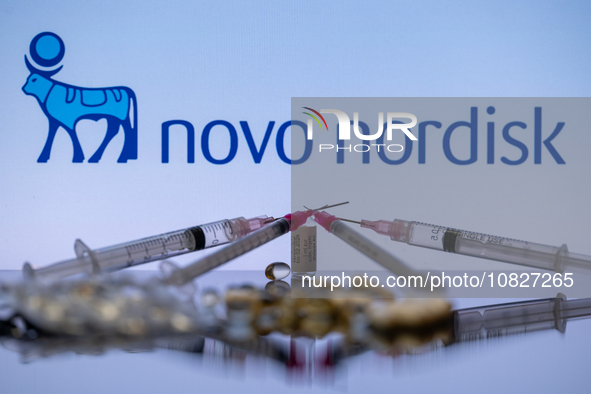 The Novo Nordisk pharmaceutical logo is being displayed on a screen alongside pills and a medical vial with a syringe in this photo illustra...