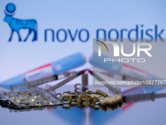 The Novo Nordisk pharmaceutical logo is being displayed on a screen alongside pills and a medical vial with a syringe in this photo illustra...