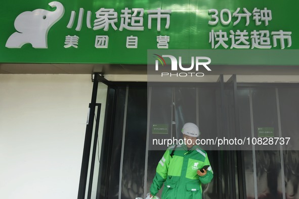 A Meituan employee is walking out of the front warehouse of Xiaoxiang Supermarket to deliver goods to customers in Hangzhou, Zhejiang Provin...