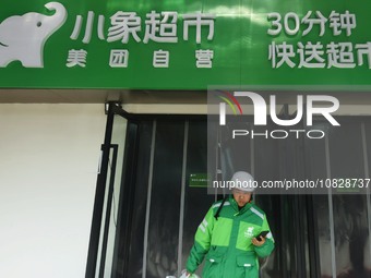 A Meituan employee is walking out of the front warehouse of Xiaoxiang Supermarket to deliver goods to customers in Hangzhou, Zhejiang Provin...