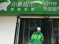 A Meituan employee is walking out of the front warehouse of Xiaoxiang Supermarket to deliver goods to customers in Hangzhou, Zhejiang Provin...