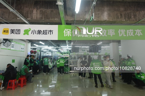 A Meituan employee is walking out of the front warehouse of Xiaoxiang Supermarket to deliver goods to customers in Hangzhou, Zhejiang Provin...