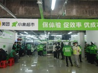 A Meituan employee is walking out of the front warehouse of Xiaoxiang Supermarket to deliver goods to customers in Hangzhou, Zhejiang Provin...