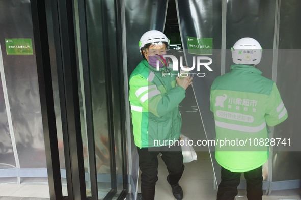 A Meituan employee is walking out of the front warehouse of Xiaoxiang Supermarket to deliver goods to customers in Hangzhou, Zhejiang Provin...