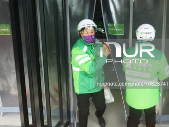 A Meituan employee is walking out of the front warehouse of Xiaoxiang Supermarket to deliver goods to customers in Hangzhou, Zhejiang Provin...