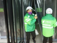 A Meituan employee is walking out of the front warehouse of Xiaoxiang Supermarket to deliver goods to customers in Hangzhou, Zhejiang Provin...