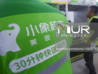 A Meituan employee is walking out of the front warehouse of Xiaoxiang Supermarket to deliver goods to customers in Hangzhou, Zhejiang Provin...