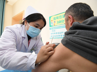 A medical worker is inoculating a citizen against influenza at a community health service center in Guiyang, Guizhou Province, China, on Dec...