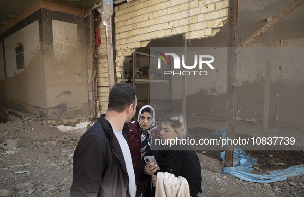 An Iranian family is standing together in front of destroyed shops while visiting the flooded village of Imamzadeh Davood in the northwester...