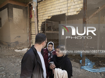 An Iranian family is standing together in front of destroyed shops while visiting the flooded village of Imamzadeh Davood in the northwester...