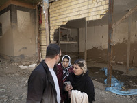 An Iranian family is standing together in front of destroyed shops while visiting the flooded village of Imamzadeh Davood in the northwester...