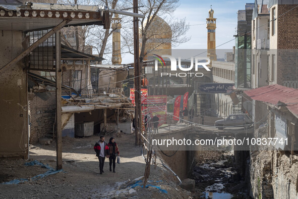 An Iranian couple is looking at destroyed shops as they walk along a collapsed street while visiting the flooded village of Imamzadeh Davood...