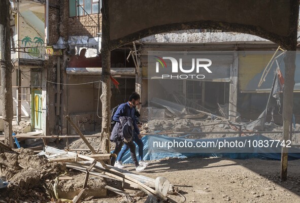 An Iranian man and woman are walking past destroyed shops along a collapsed street while visiting the flooded village of Imamzadeh Davood in...