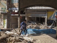 An Iranian man and woman are walking past destroyed shops along a collapsed street while visiting the flooded village of Imamzadeh Davood in...