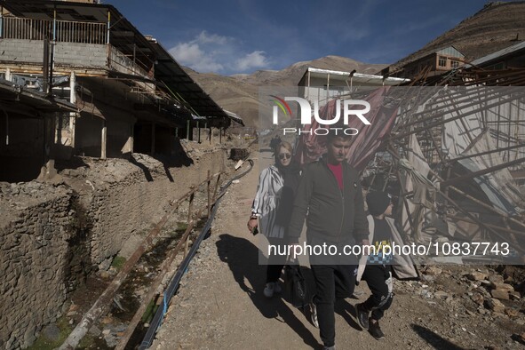 An Iranian family is walking past destroyed shops along a collapsed street while visiting the flooded village of Imamzadeh Davood in the nor...