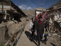 An Iranian family is walking past destroyed shops along a collapsed street while visiting the flooded village of Imamzadeh Davood in the nor...