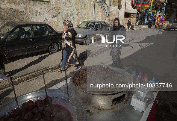 Two Iranian female tourists are walking past a vendor at a bazaar while visiting the flooded village of Imamzadeh Davood in the northwestern...