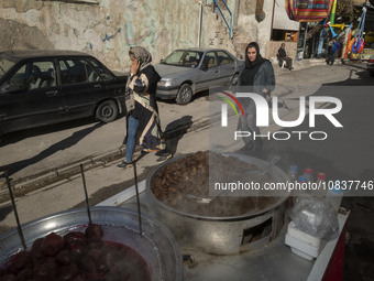 Two Iranian female tourists are walking past a vendor at a bazaar while visiting the flooded village of Imamzadeh Davood in the northwestern...