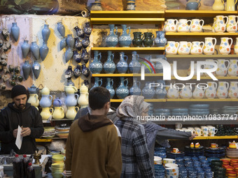 An Iranian woman is pointing at clay dishes while shopping at a bazaar in the flooded village of Imamzadeh Davood, in the northwestern part...