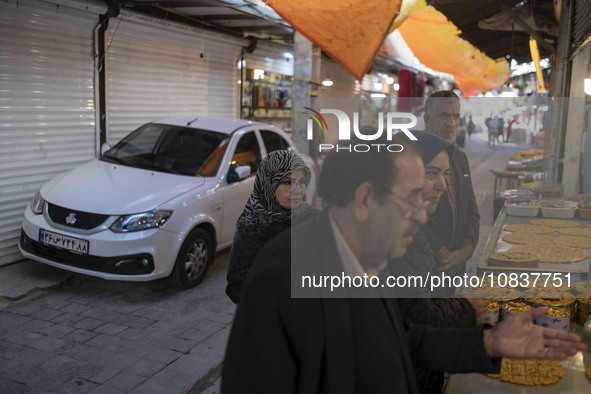 An Iranian family is standing in front of a traditional sweet shop at a bazaar in the flooded village of Imamzadeh Davood in the northwester...