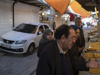 An Iranian family is standing in front of a traditional sweet shop at a bazaar in the flooded village of Imamzadeh Davood in the northwester...