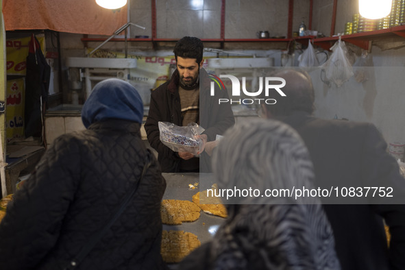 An Iranian salesman is putting a box of traditional sweets into a plastic bag for his customers at a bazaar in the flooded village of Imamza...