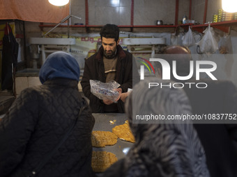 An Iranian salesman is putting a box of traditional sweets into a plastic bag for his customers at a bazaar in the flooded village of Imamza...