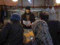 An Iranian salesman is putting a box of traditional sweets into a plastic bag for his customers at a bazaar in the flooded village of Imamza...