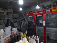 An Iranian man and an elderly veiled woman are shopping at a bazaar in the flooded village of Imamzadeh Davood in the northwestern part of T...