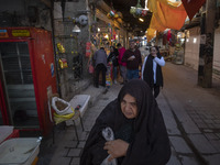 An elderly Iranian woman is walking through a bazaar in the flooded village of Imamzadeh Davood, in the northwestern part of Tehran, on Dece...