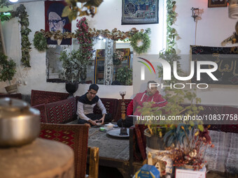 An Iranian man is puffing on a water pipe while sitting next to his friend at a traditional restaurant in the flooded village of Imamzadeh D...