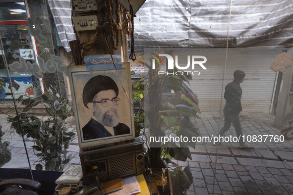 An Iranian man is walking past a portrait of Iran's Supreme Leader, Ayatollah Ali Khamenei, in the flooded village of Imamzadeh Davood in th...