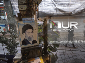 An Iranian man is walking past a portrait of Iran's Supreme Leader, Ayatollah Ali Khamenei, in the flooded village of Imamzadeh Davood in th...