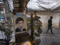 An Iranian man is walking past a portrait of Iran's Supreme Leader, Ayatollah Ali Khamenei, in the flooded village of Imamzadeh Davood in th...