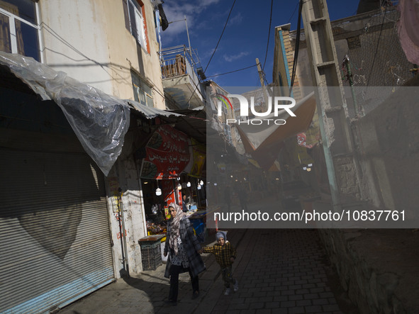 An Iranian woman and her young son are walking through a bazaar while visiting the flooded village of Imamzadeh Davood in the northwestern p...