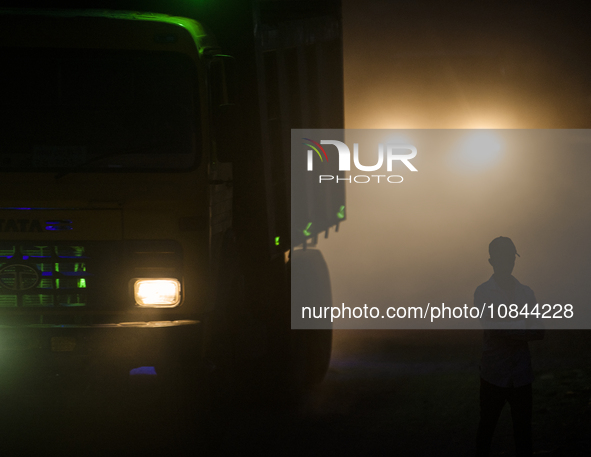 A pedestrian is standing along a dusty road in Dhaka, Bangladesh, on December 5, 2023. 