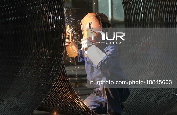 A worker is welding steel components of air separation equipment in Huzhou, Zhejiang Province, China, on December 12, 2023. 