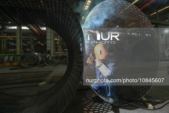 A worker is welding steel components of air separation equipment in Huzhou, Zhejiang Province, China, on December 12, 2023. 