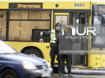 In Kyiv, Ukraine, on December 11, 2023, a police officer is talking to the driver of a bus that is operating between the closed metro statio...