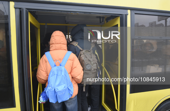 Passengers are getting on a bus that is operating between the closed metro stations of the Blue Line in Kyiv, Ukraine, on December 11, 2023....