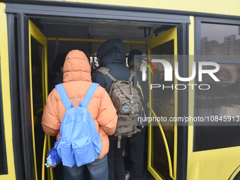 Passengers are getting on a bus that is operating between the closed metro stations of the Blue Line in Kyiv, Ukraine, on December 11, 2023....