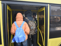 Passengers are getting on a bus that is operating between the closed metro stations of the Blue Line in Kyiv, Ukraine, on December 11, 2023....