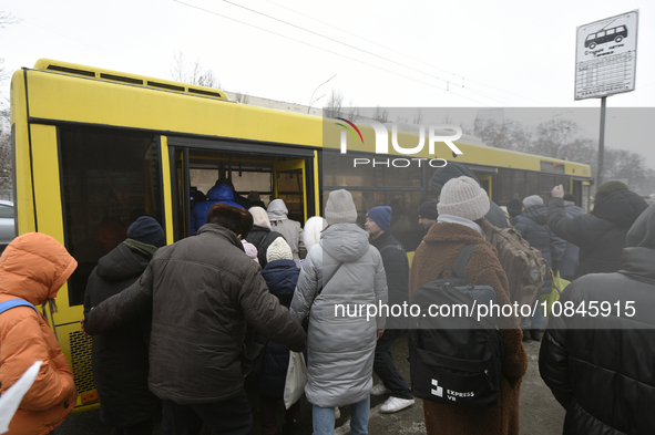 Passengers are getting on a bus that is operating between the closed metro stations of the Blue Line in Kyiv, Ukraine, on December 11, 2023....